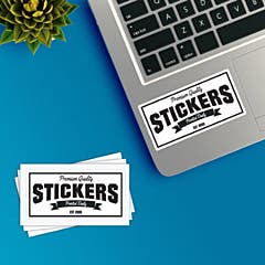 Customizable rectangle stickers sitting on desk with one already applied to a laptop. 