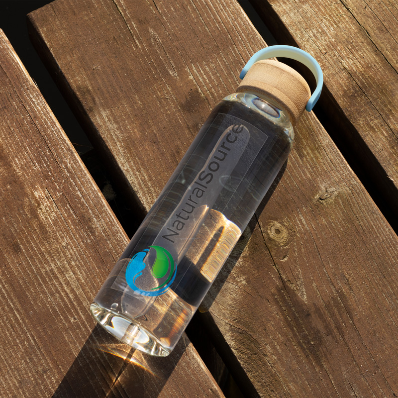 A clear sticker with an eco-brand logo applied to a glass water bottle, perfect for reusable items.